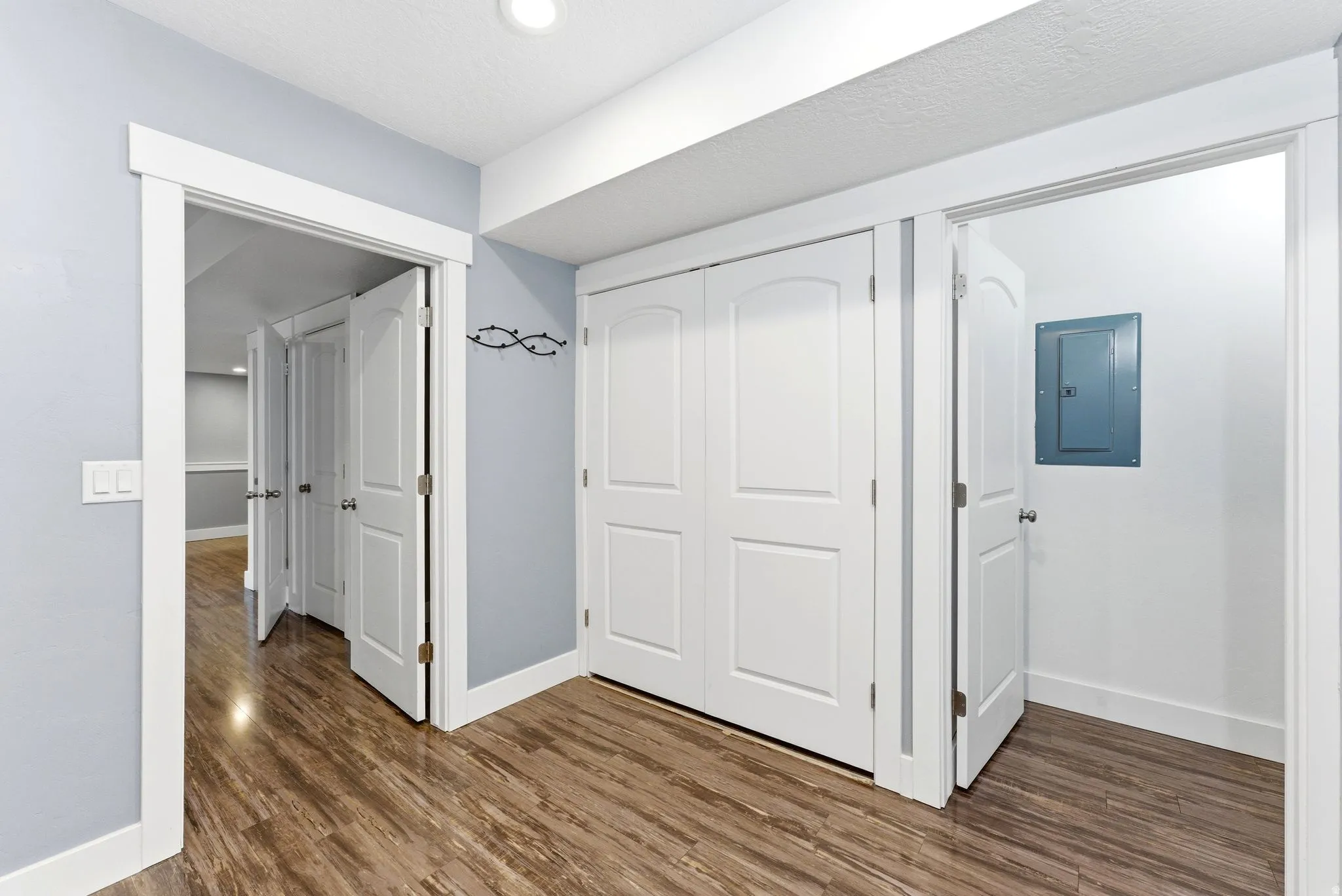 Laundry room featuring wood-finish flooring, light blue wall paint, white trim, and a bi-fold closet