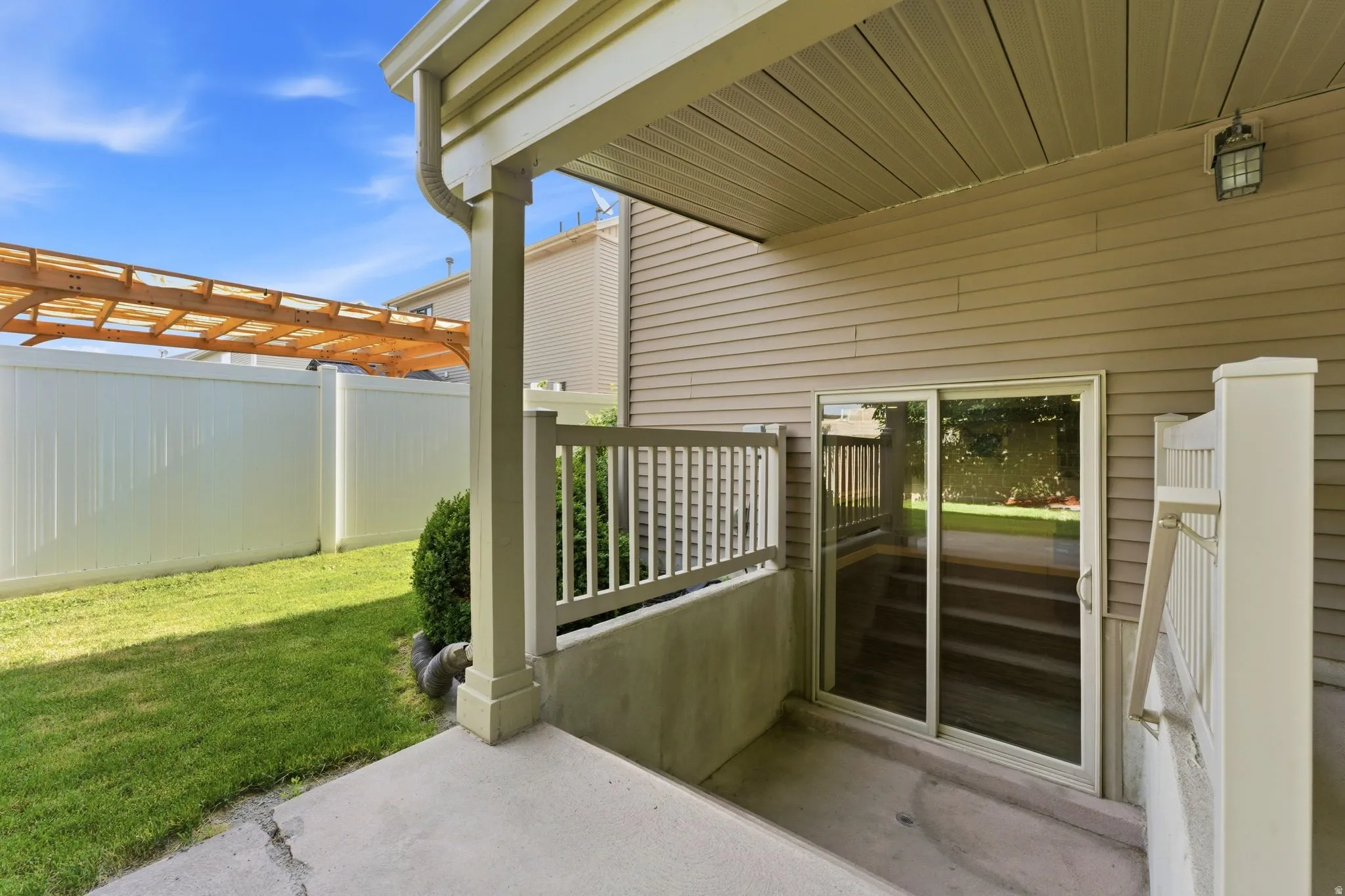 Patio area featuring a sliding glass door entry, concrete flooring, and a privacy fence