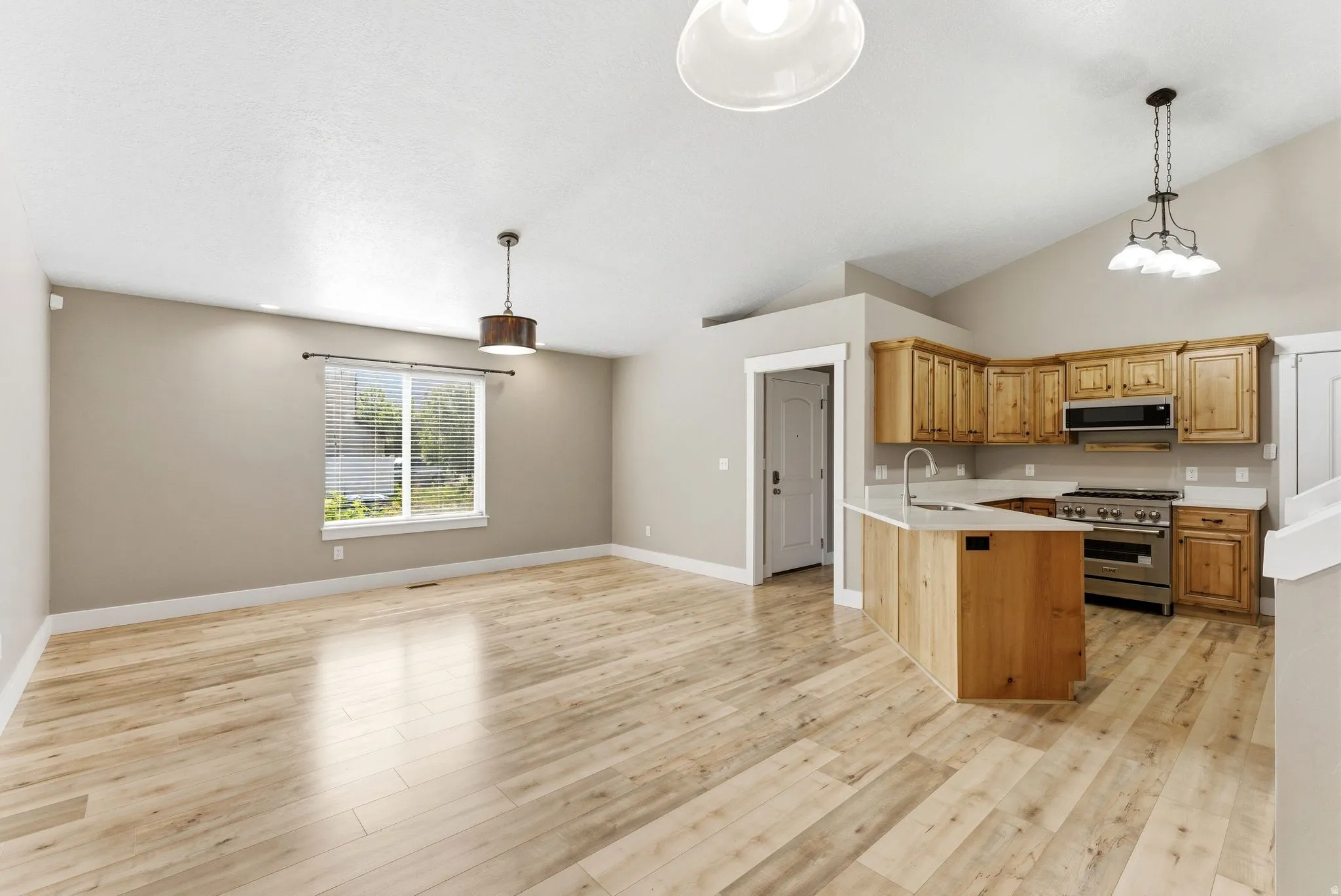 Open-concept living area featuring new LVP flooring, vaulted ceilings, and a modern kitchen