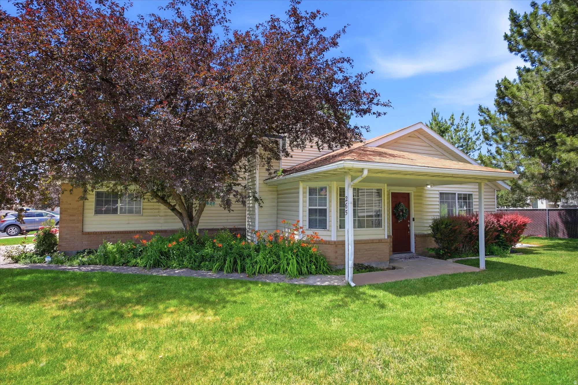 Single-story residence featuring a covered front porch with white columns, light-toned siding, and a red entry door