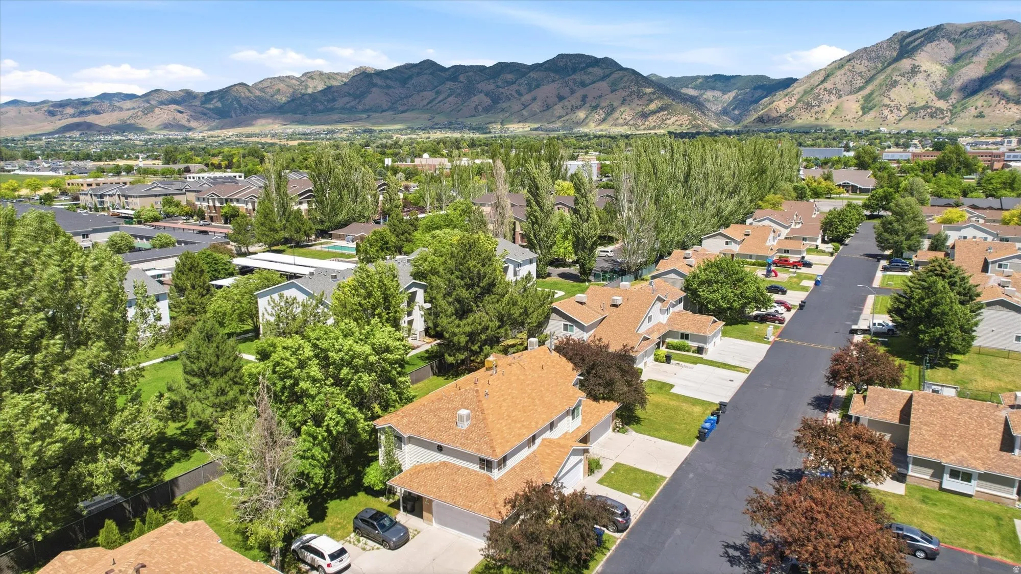 Residential street featuring a collection of properties with varied rooflines and landscaping, set against a backdrop of distant mountains