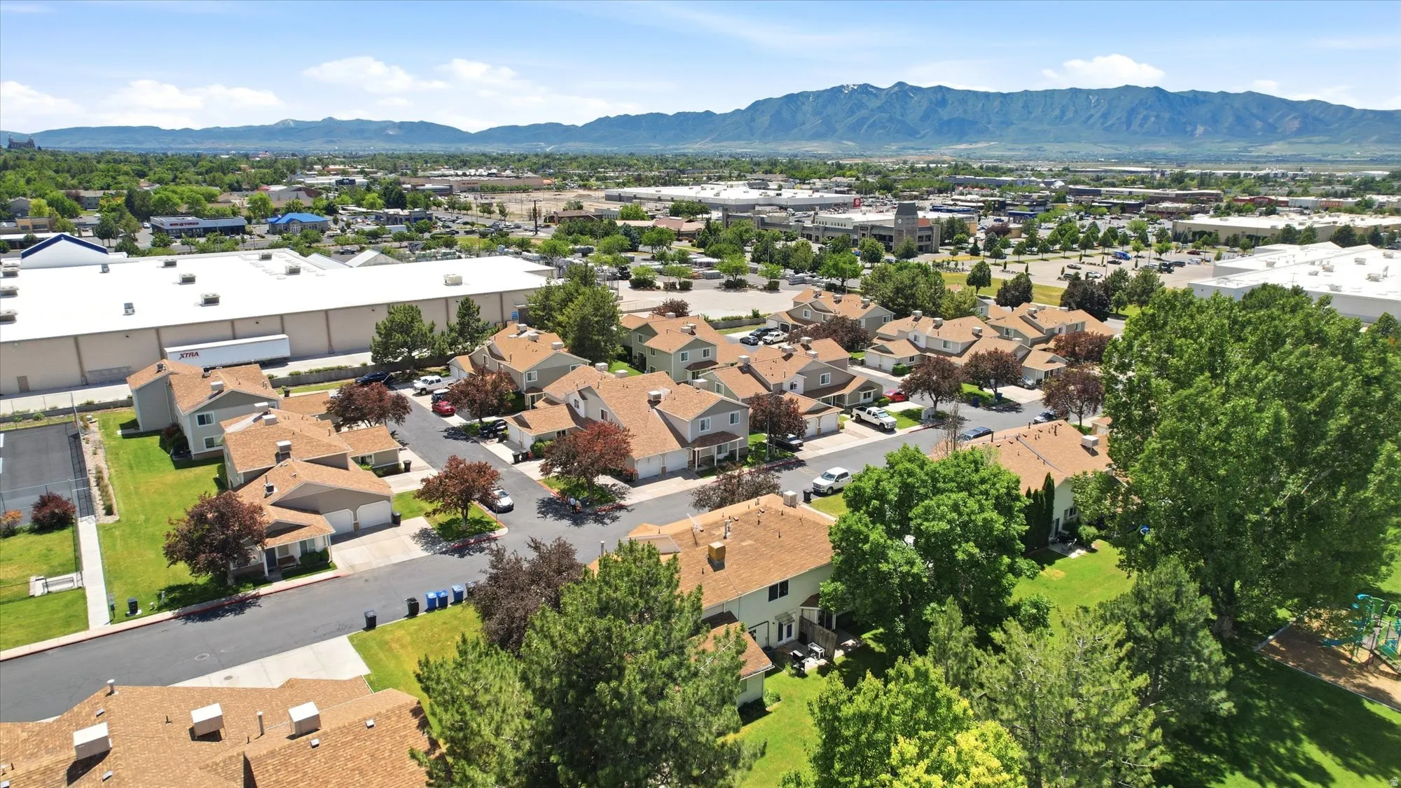 Residential community featuring mature trees, paved streets, and a mountainous backdrop