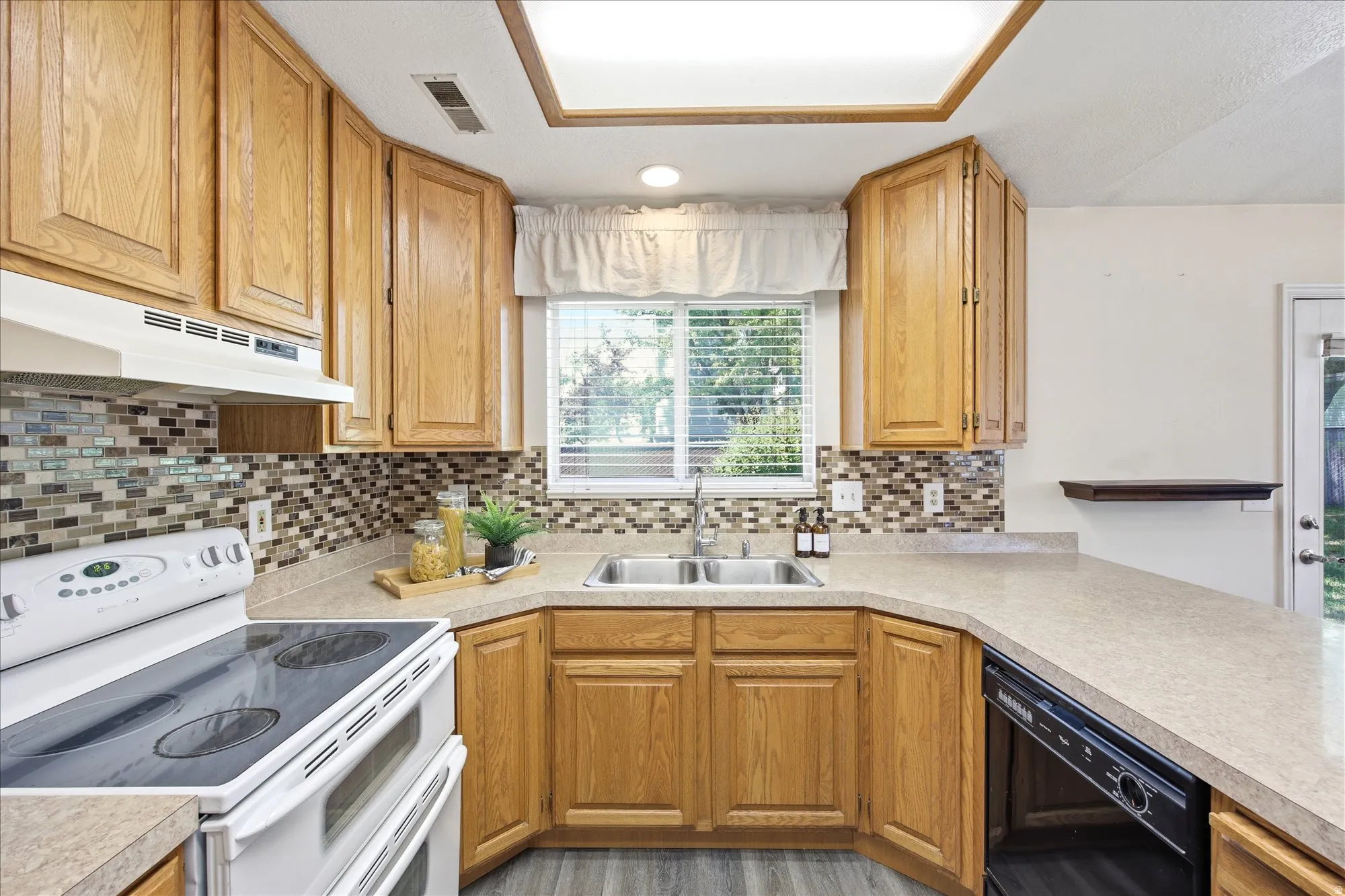Kitchen with light wood cabinetry, a mosaic tile backsplash, and light-colored countertops