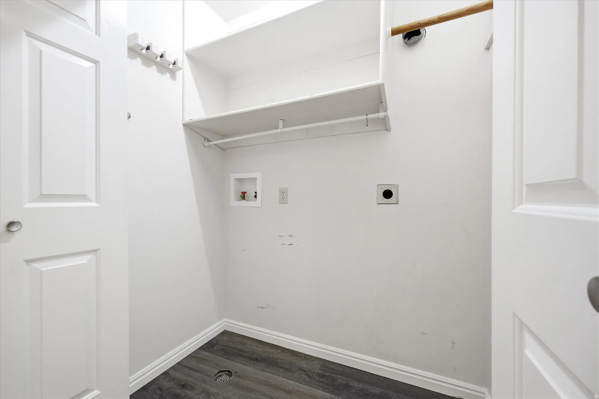 Dedicated laundry area featuring wood-finish flooring and white baseboards