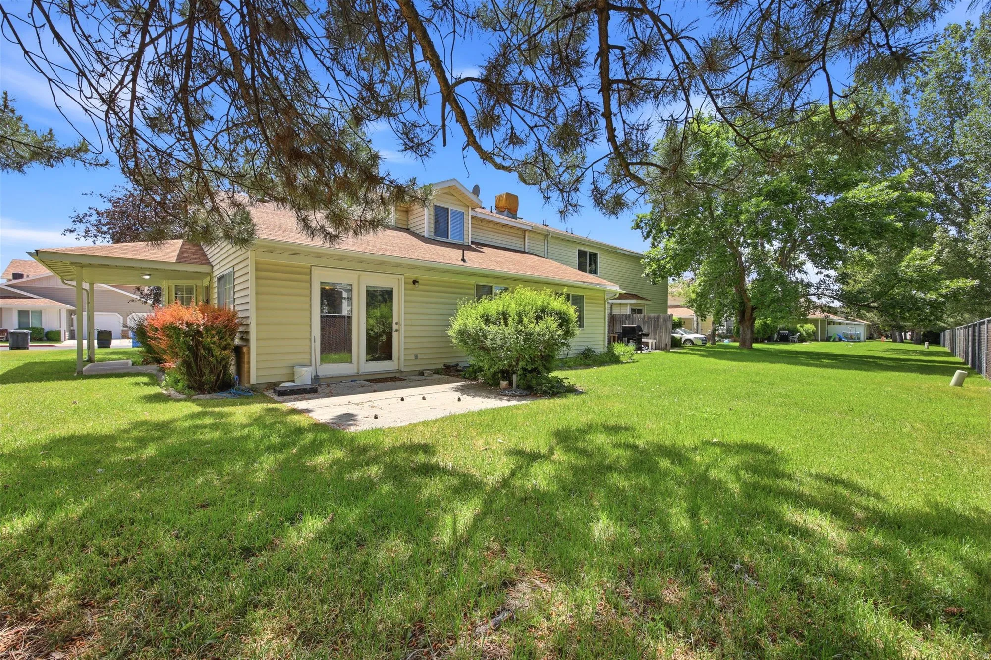 Expansive green lawn with mature trees and a concrete patio