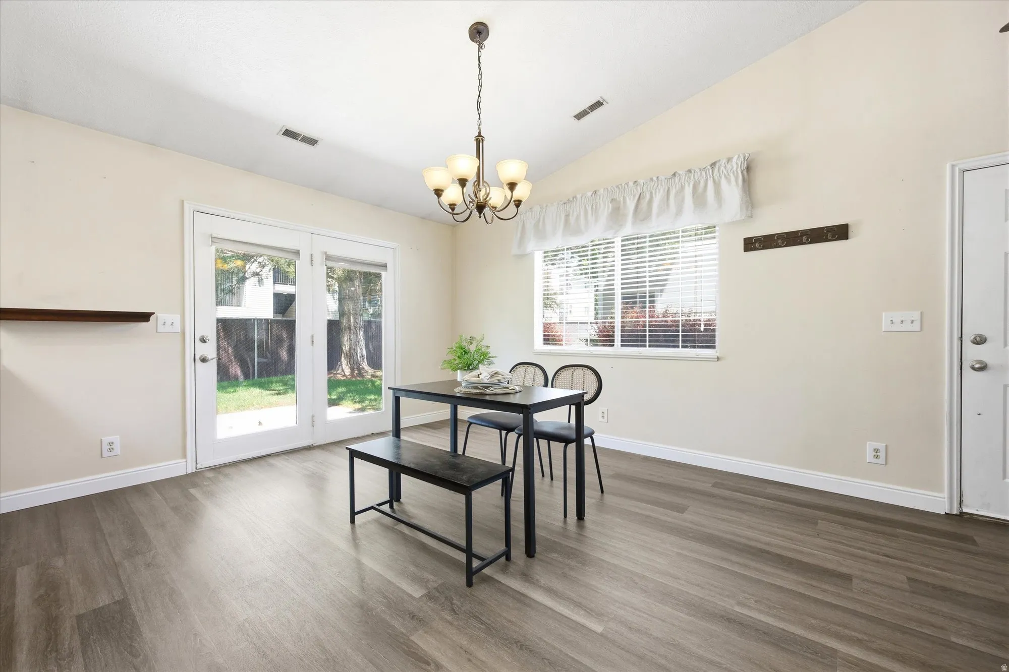 Dining area featuring wood-finish flooring, a vaulted ceiling, and a chandelier