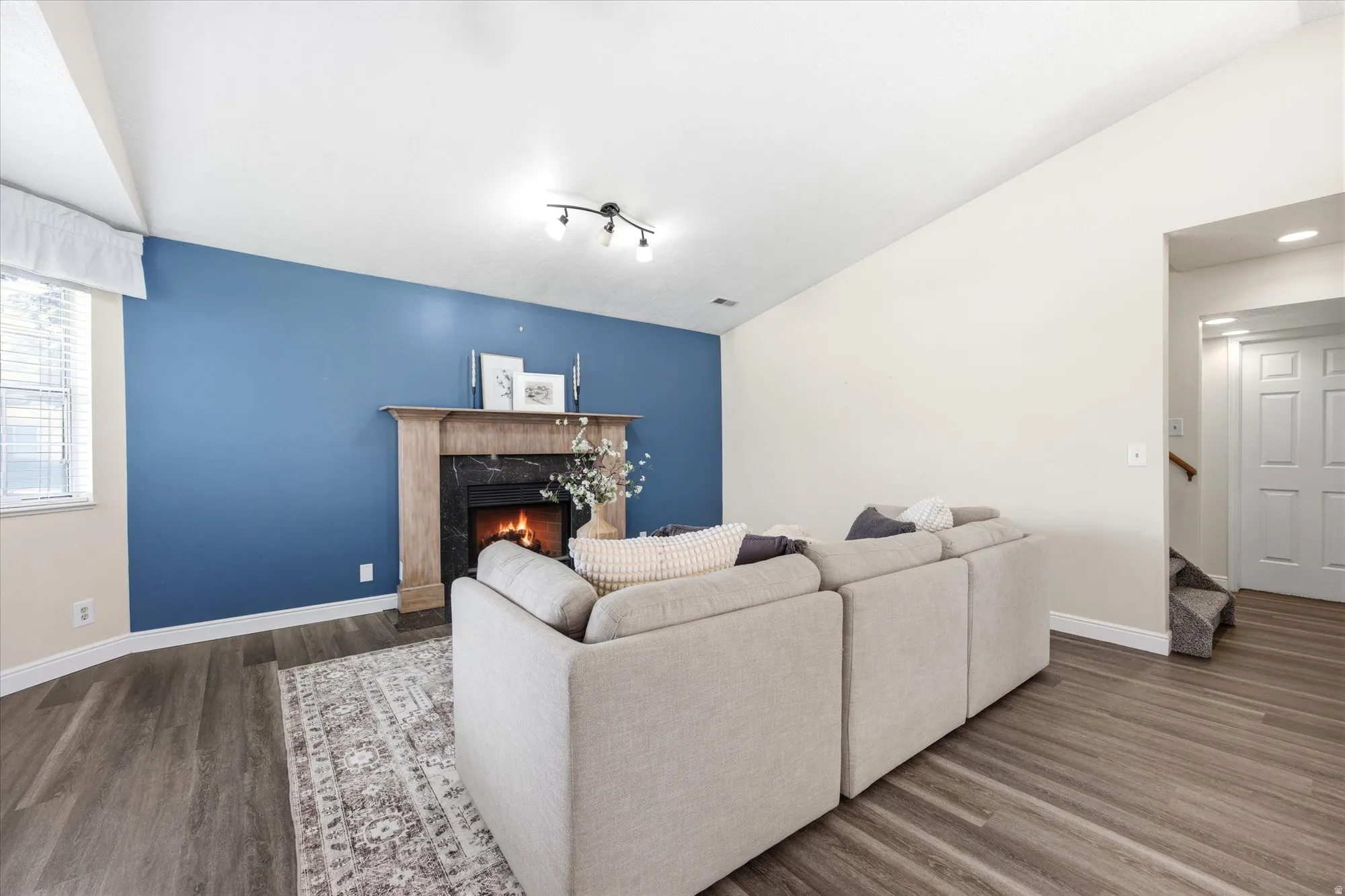 Living area featuring a fireplace with a wood mantle and dark stone surround, vaulted ceilings, and wood-finish flooring