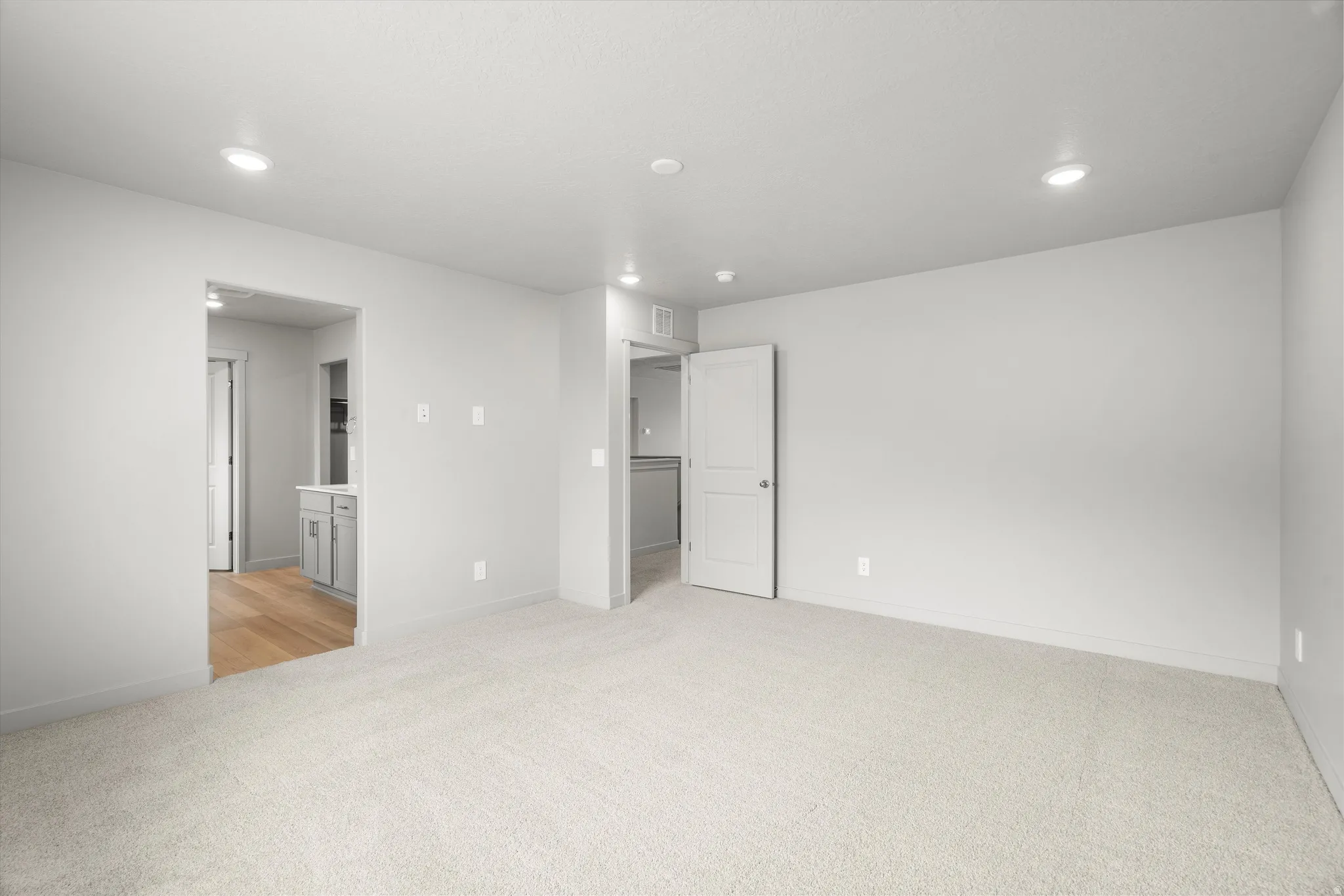 Spacious room featuring light-colored carpeting, recessed lighting, and neutral wall tones