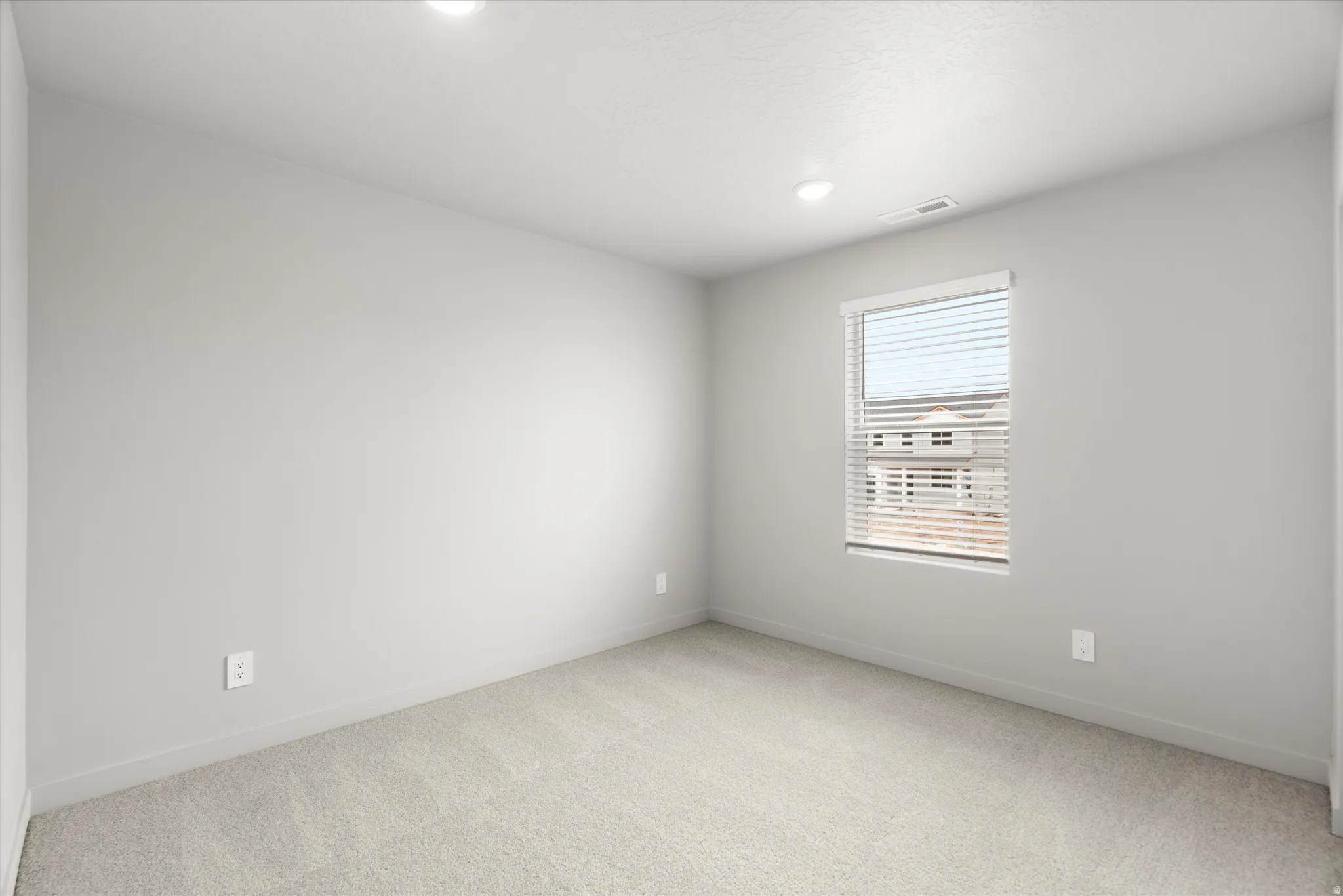 Room with light gray walls, light carpet flooring, a window with blinds, and recessed lighting