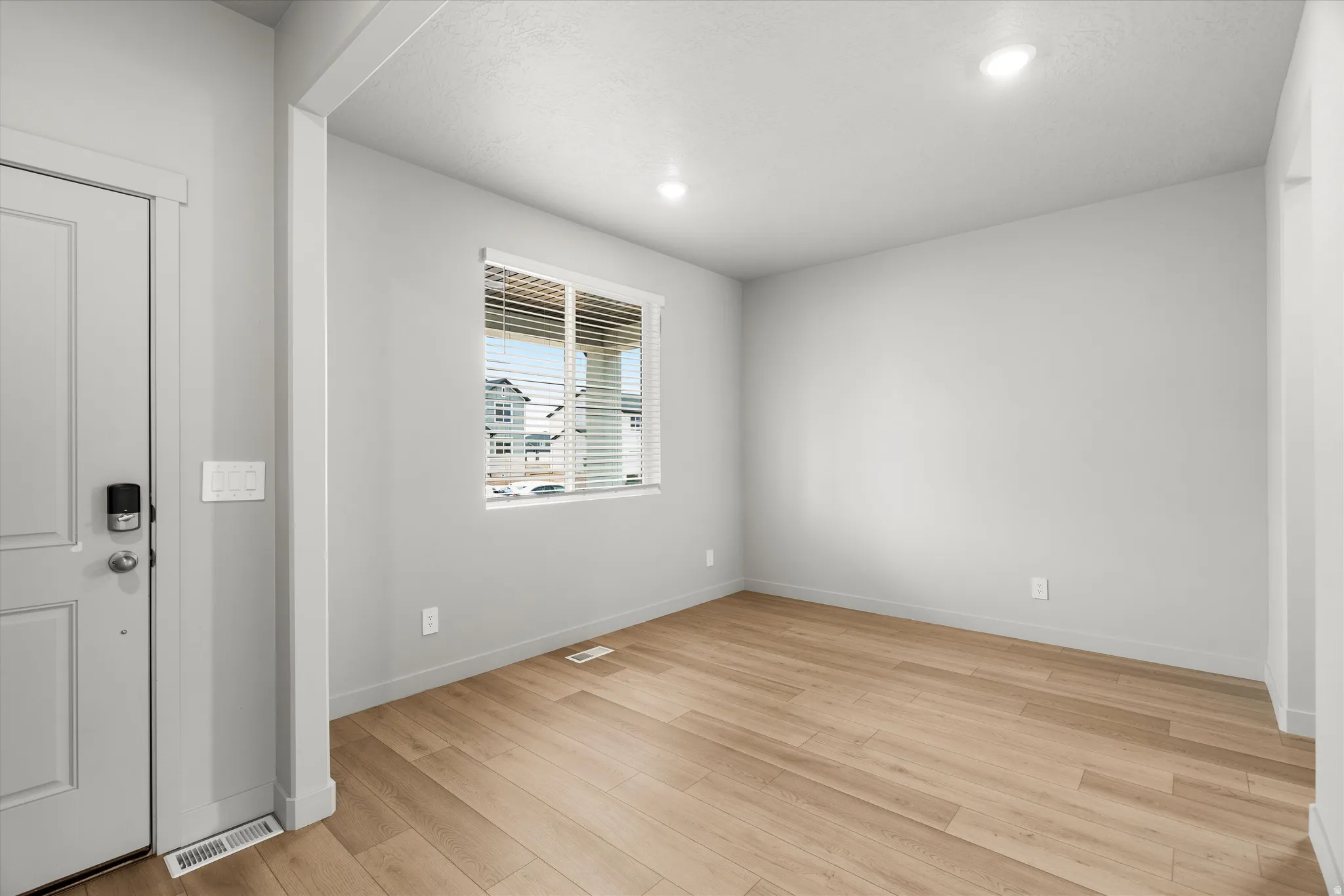 Entryway and versatile room featuring wood-finish flooring, recessed lighting, and a window with blinds