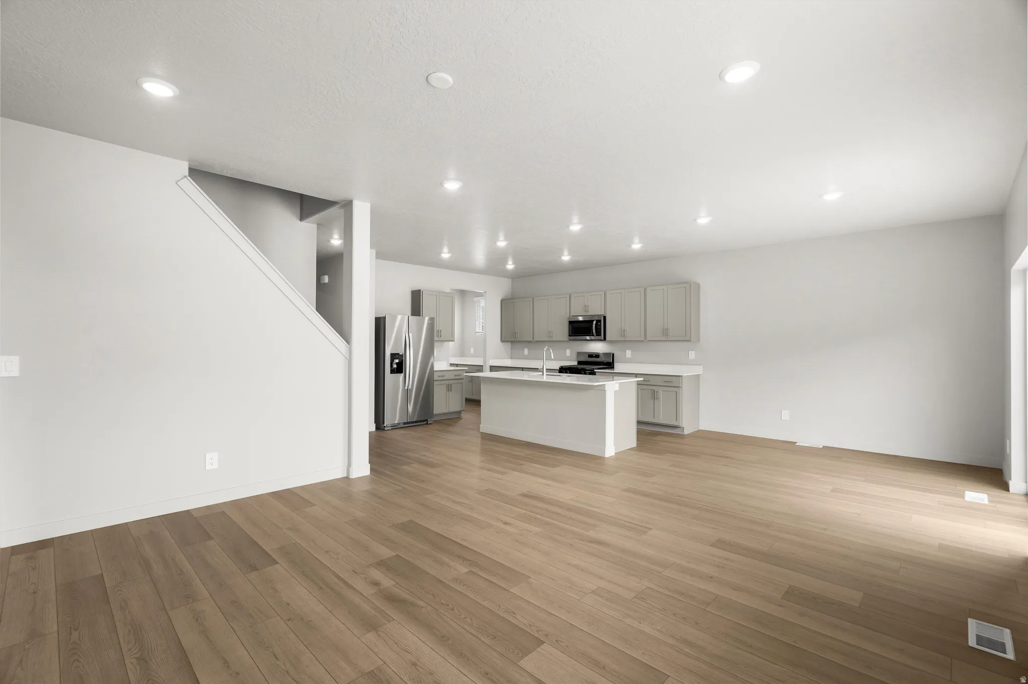 Open-concept living area with wood-finish flooring, recessed lighting, and a neutral color palette