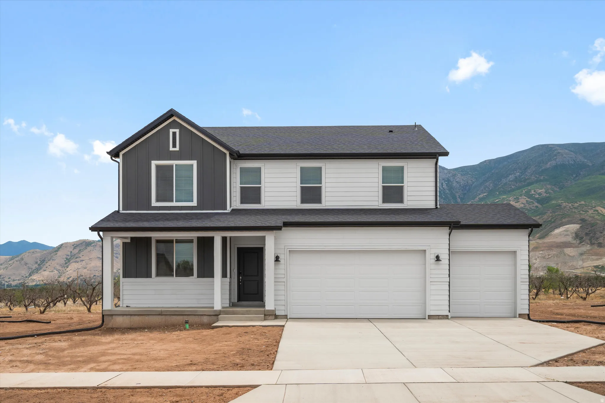 Contemporary two-story exterior featuring a two-tone facade, covered front porch, and a three-car garage