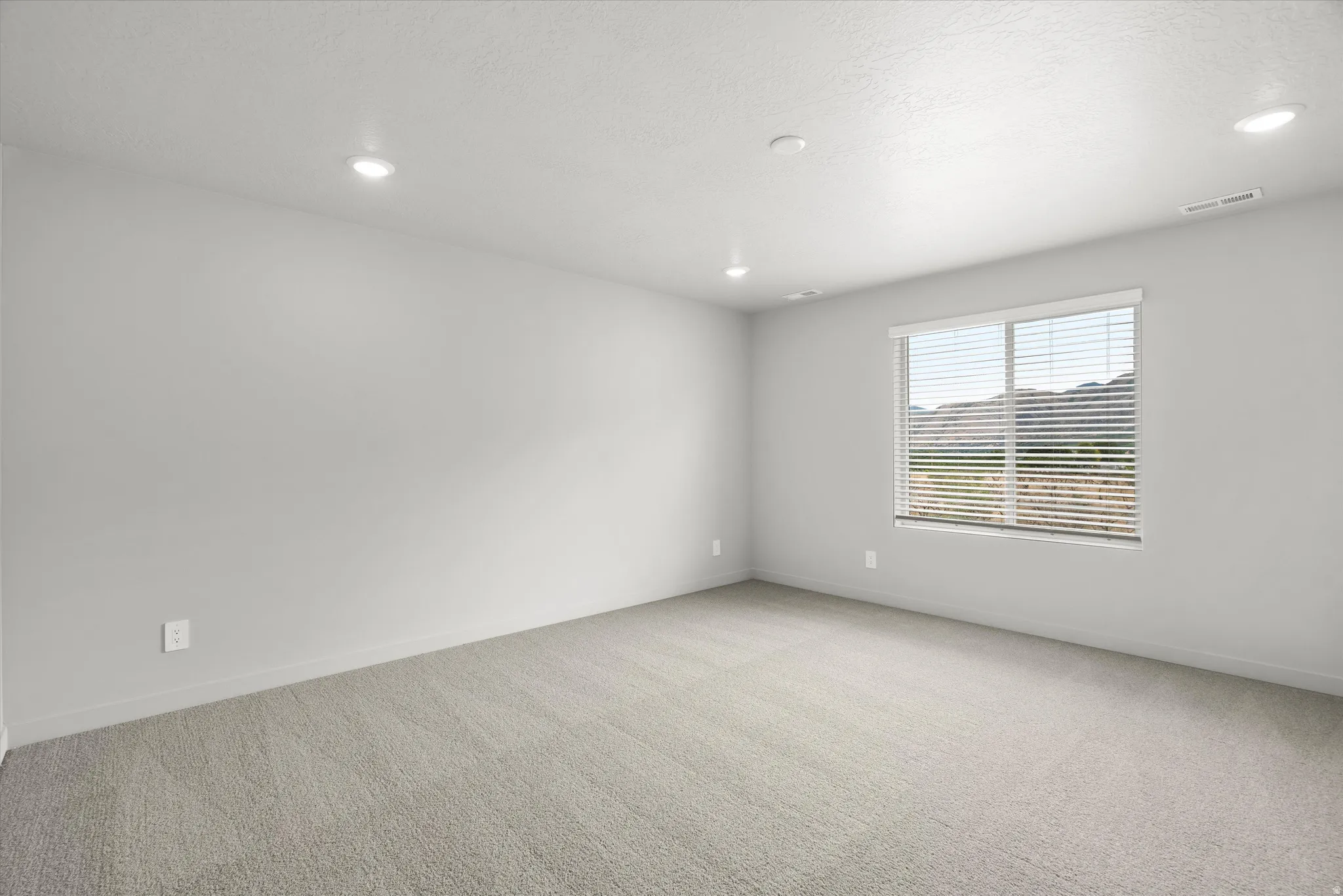 Carpeted room with recessed lighting and a window featuring horizontal blinds