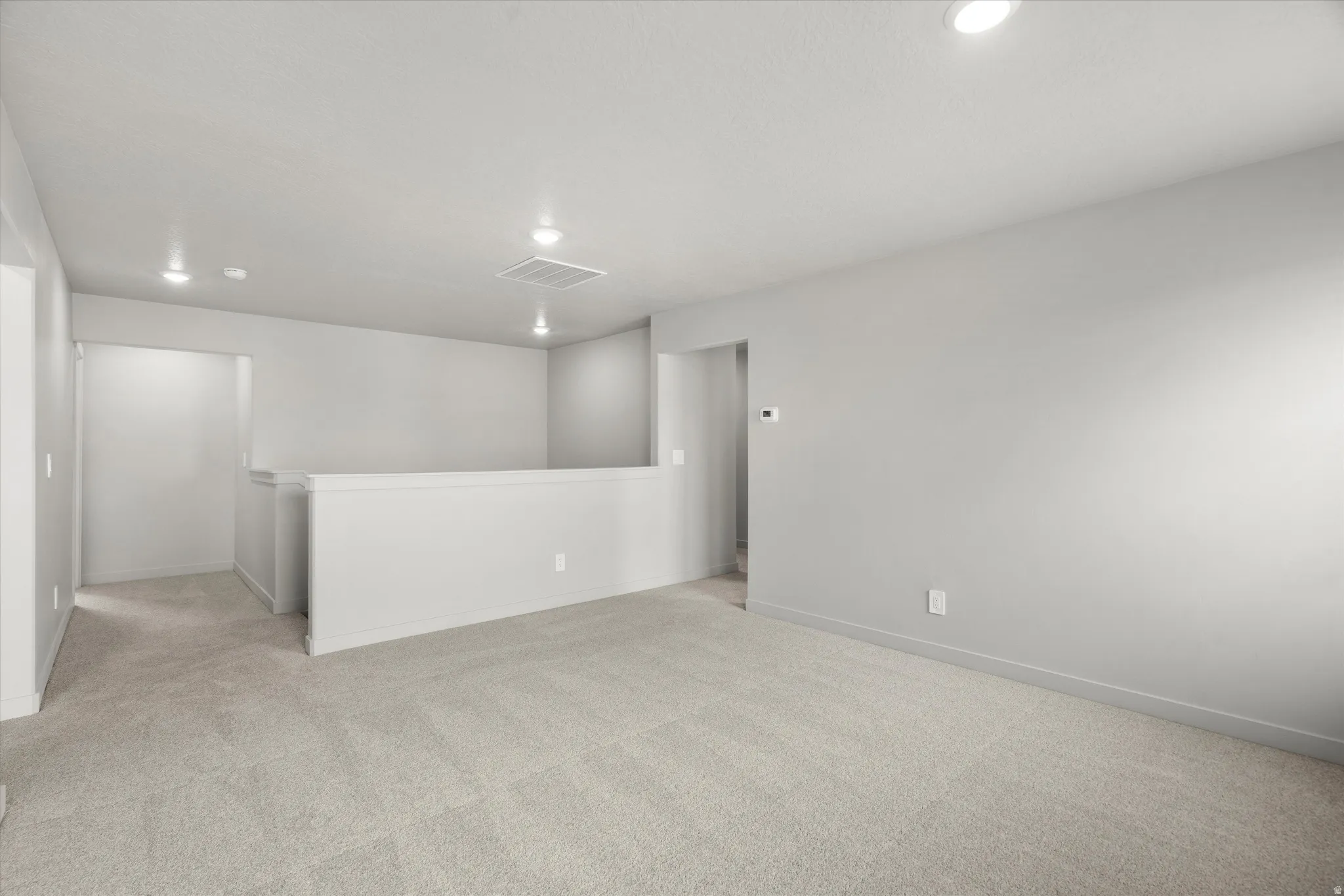 Open loft area featuring neutral-toned carpeting and light gray wall finishes