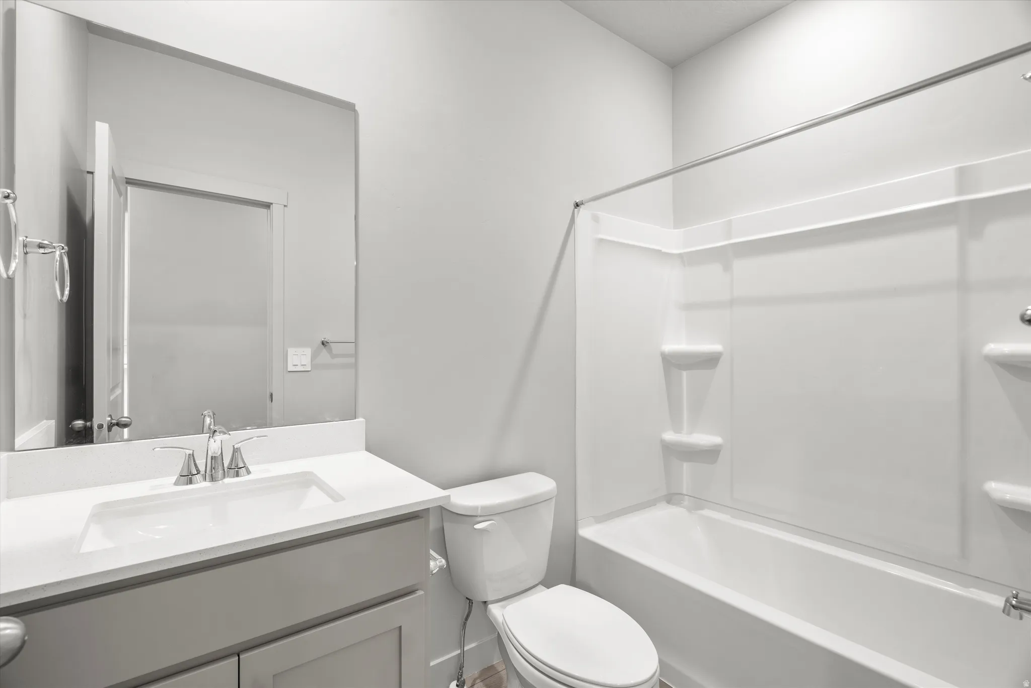 Bathroom featuring a built-in tub with shower, white shower surround, contemporary vanity with a white countertop, undermount sink, and a large wall-mounted mirror