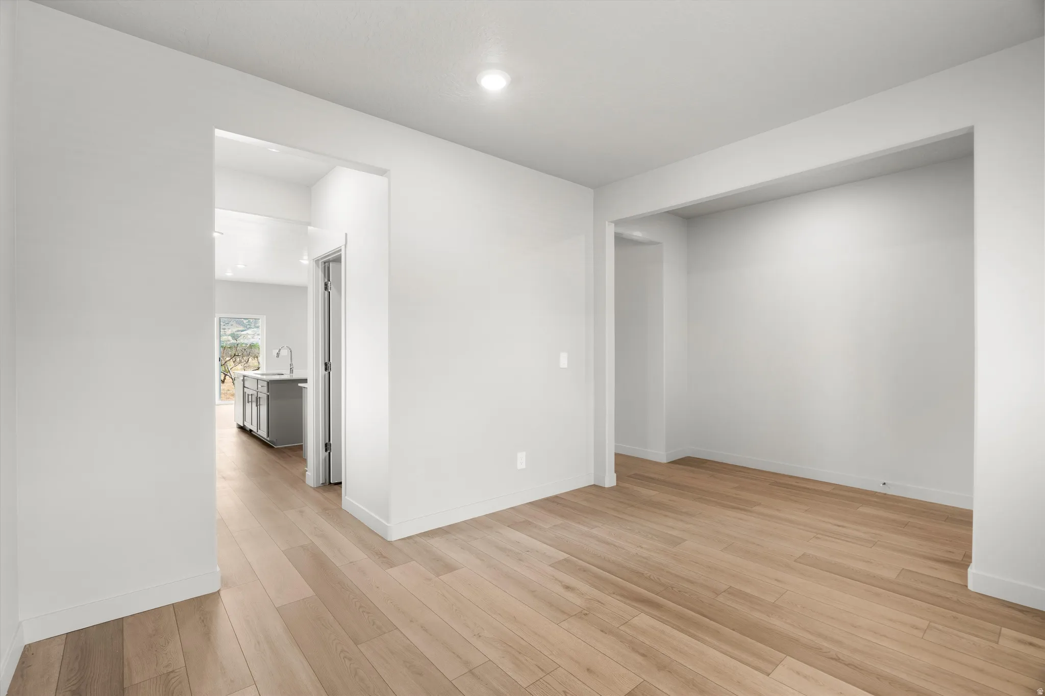 Expansive interior room featuring light wood-finish flooring and bright white walls