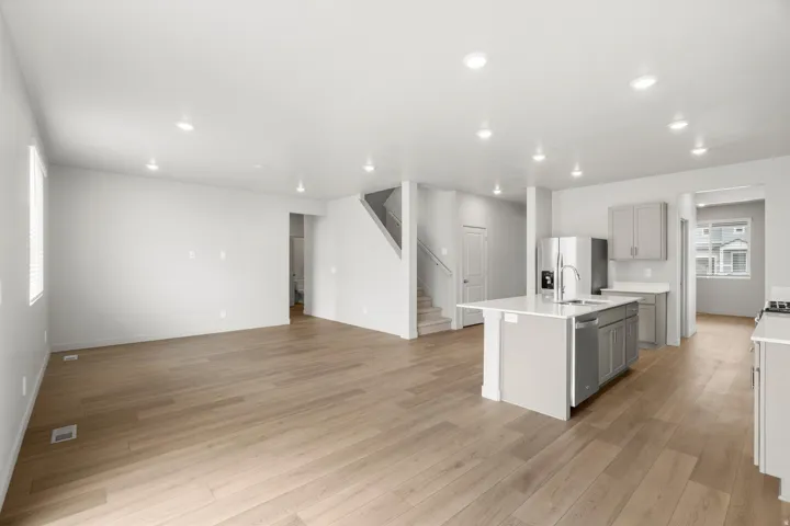 Open-concept living space featuring wood-finish flooring, recessed lighting, and a modern kitchen island with an integrated sink