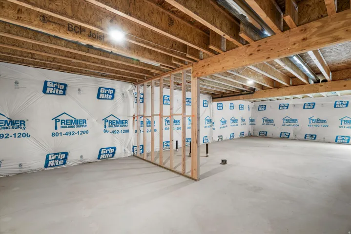 Unfinished basement space featuring exposed wood joists and concrete flooring