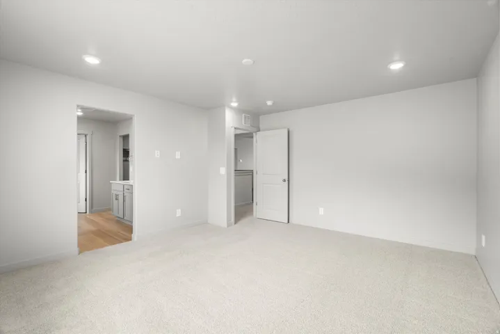 Spacious room featuring light-colored carpeting, recessed lighting, and neutral wall tones