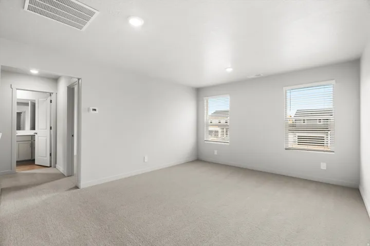 Carpeted room with recessed lighting and two windows featuring blinds