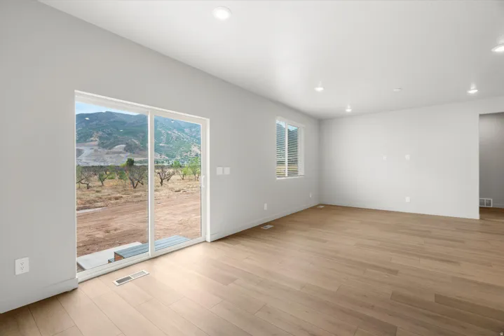 Spacious room featuring wood-finish flooring and recessed lighting
