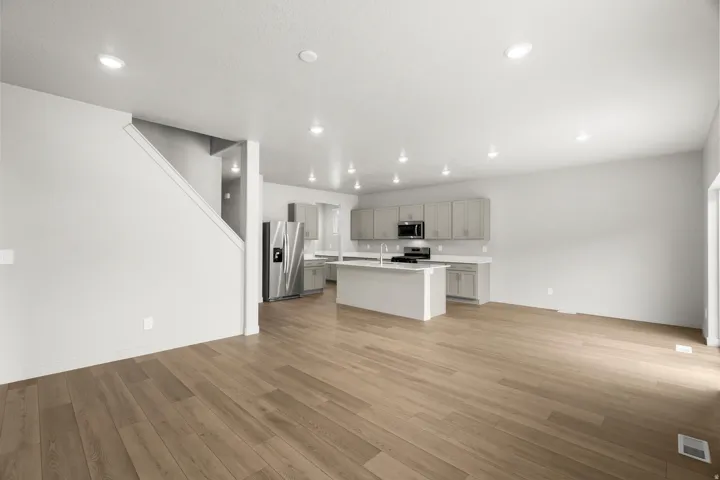 Open-concept living area with wood-finish flooring, recessed lighting, and a neutral color palette