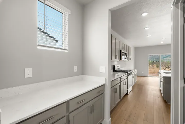 Kitchen featuring light gray cabinetry, white countertops, wood-finish flooring, recessed lighting, and a sliding glass door