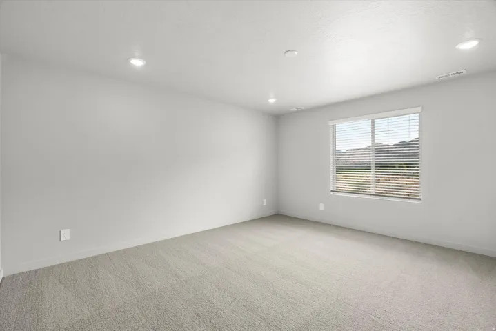 Carpeted room with recessed lighting and a window featuring horizontal blinds