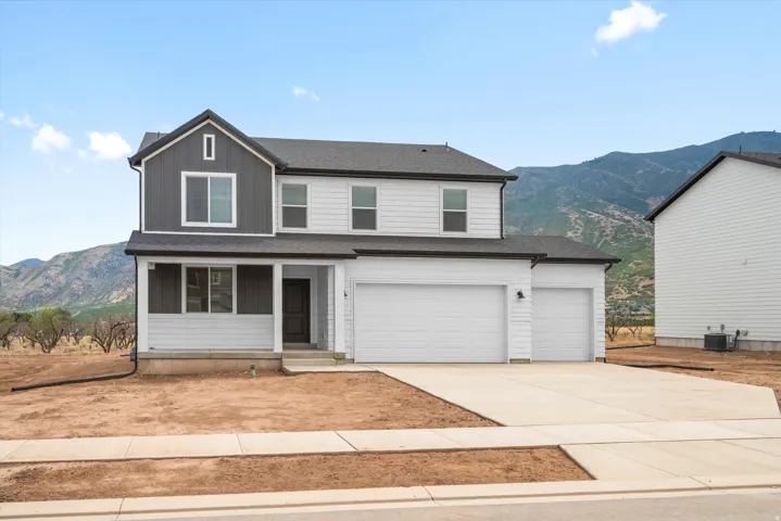 Two-story residence featuring white and dark gray siding, a covered front porch, and a two-car garage