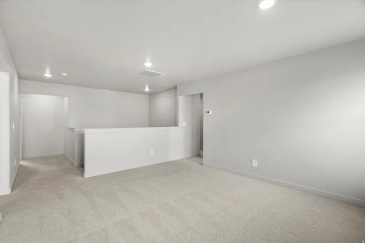 Open loft area featuring neutral-toned carpeting and light gray wall finishes