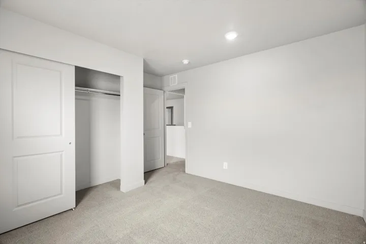 Carpeted room featuring recessed lighting, a sliding door closet with a metal hanging rod, and light-toned walls