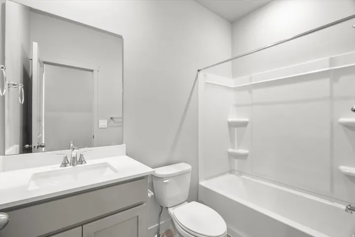 Bathroom featuring a built-in tub with shower, white shower surround, contemporary vanity with a white countertop, undermount sink, and a large wall-mounted mirror