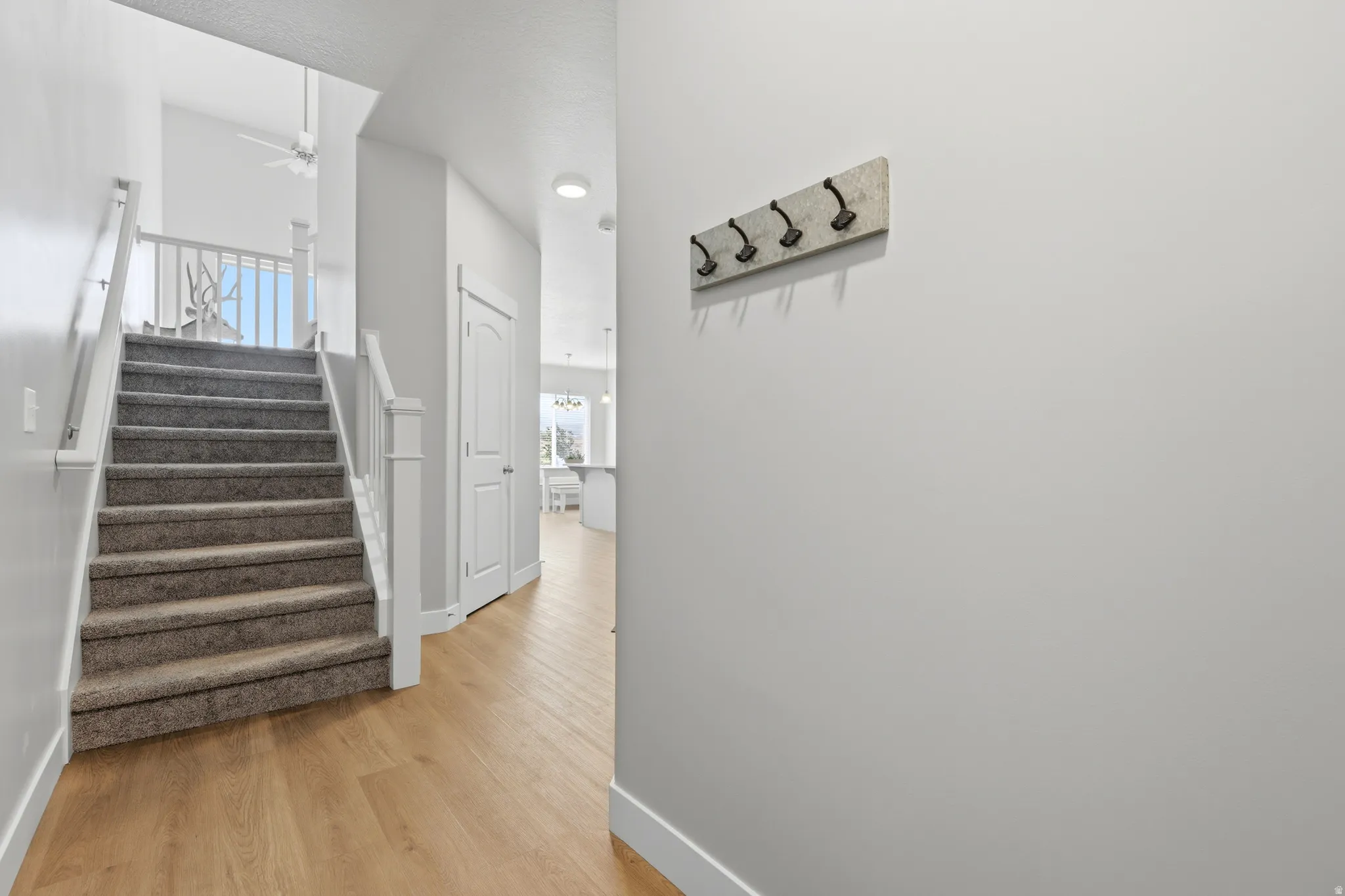 Carpeted staircase with white balusters leading to an upper landing with a ceiling fan