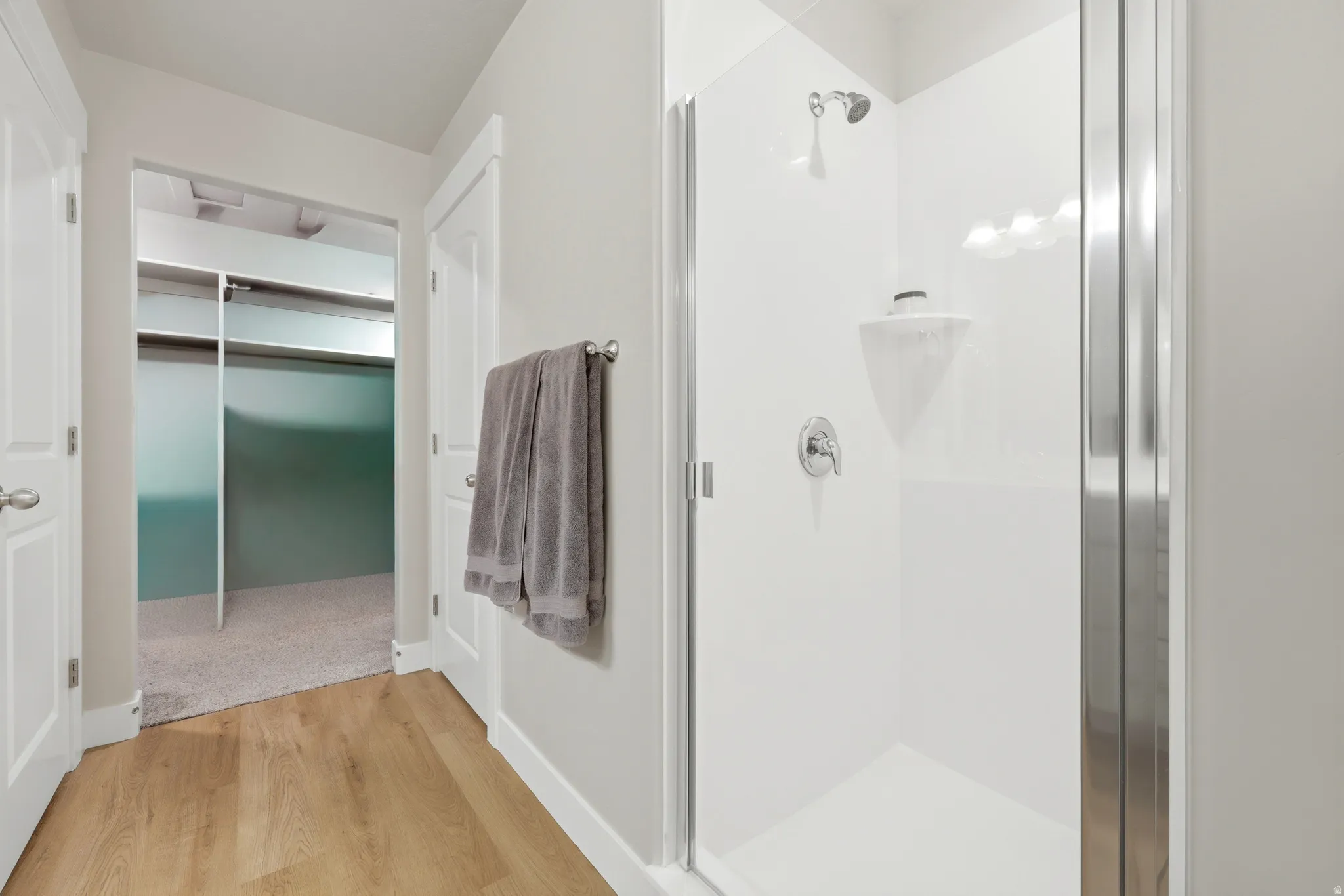 Contemporary shower enclosure with a clear glass door, chrome fixtures, and a white surround