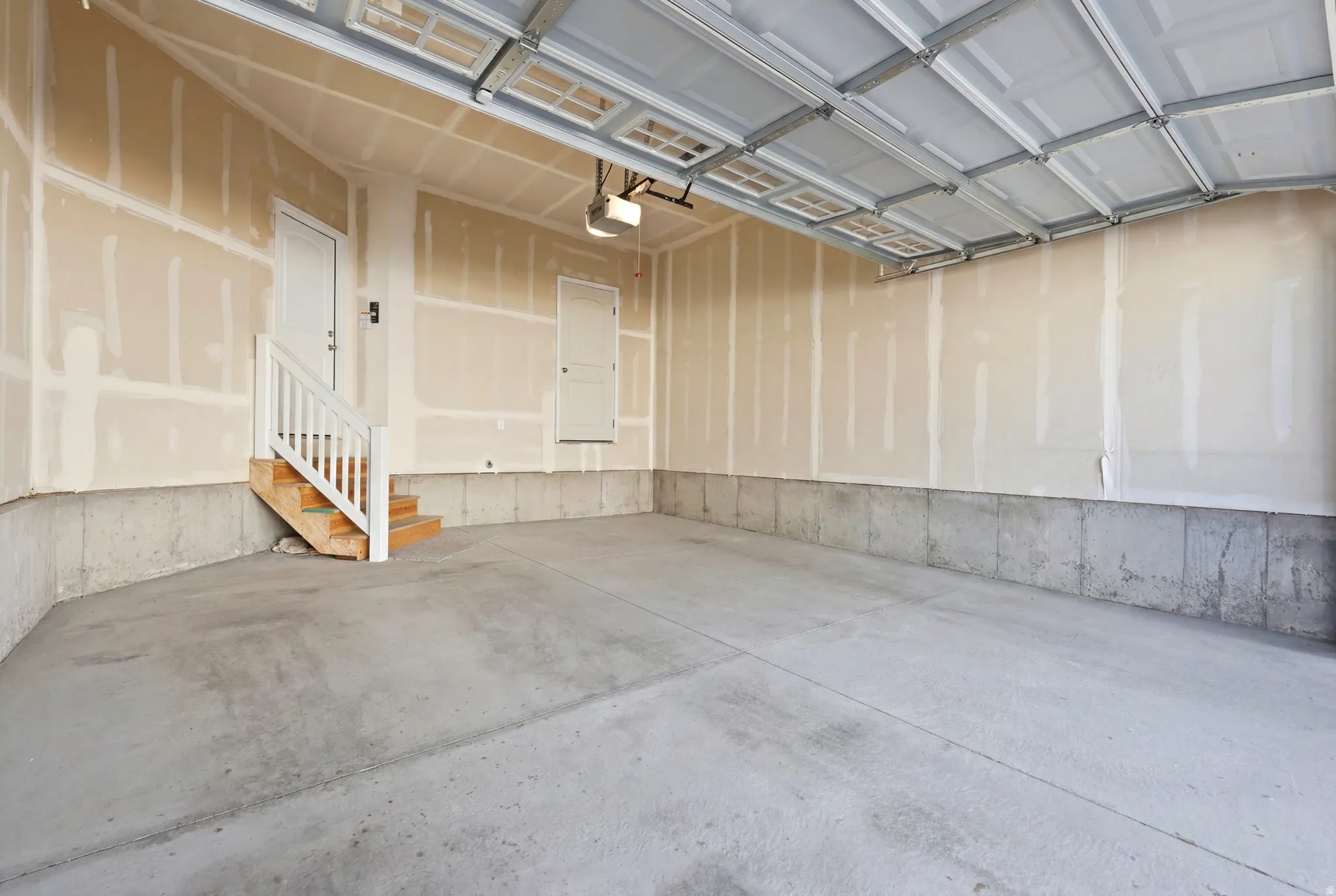 Spacious garage with a concrete floor, concrete foundation walls, and unfinished drywall