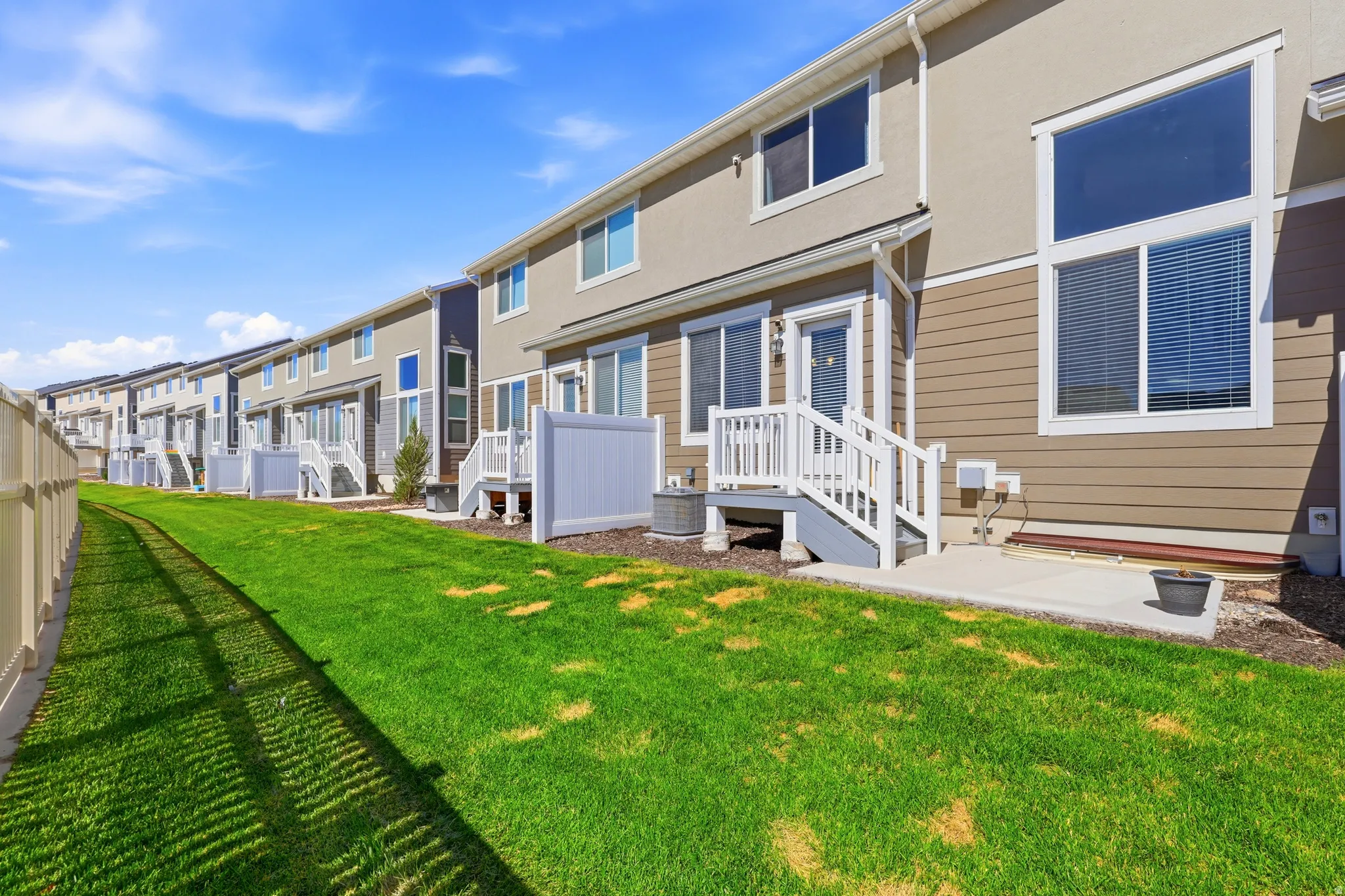 Expansive green lawn backing to a row of modern townhomes