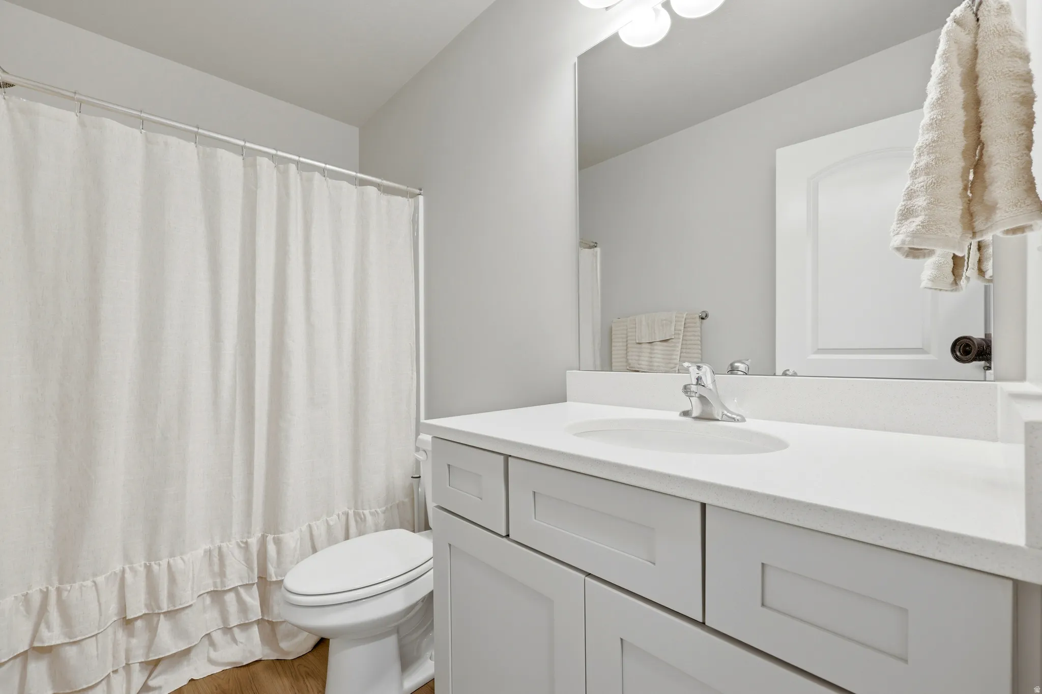 Bathroom featuring a white vanity with an integrated sink, polished chrome faucet, and a large wall-mounted mirror