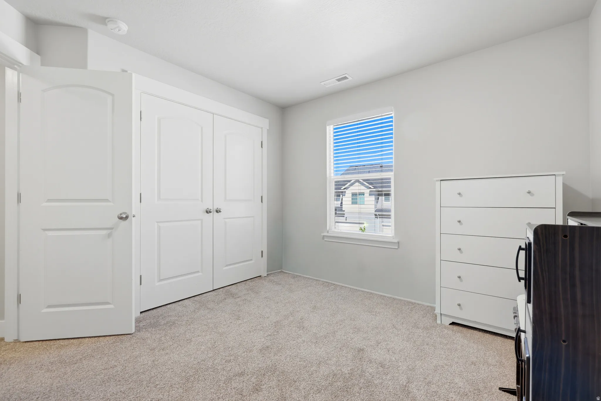 Carpeted room featuring a single window with blinds, white trim, and a white ceiling