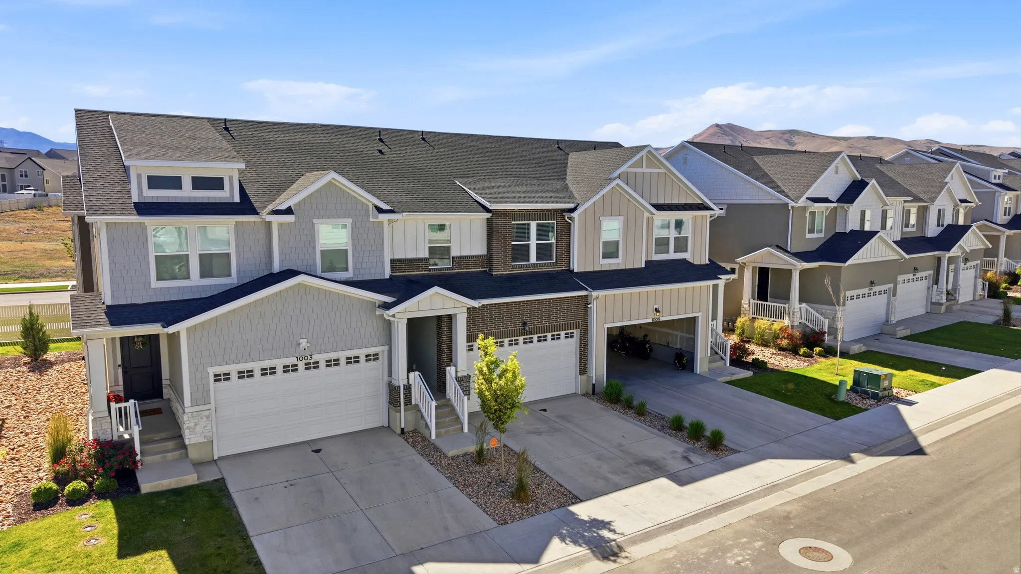 Modern townhome exterior featuring multi-toned siding, a two-car garage, and a covered front entry