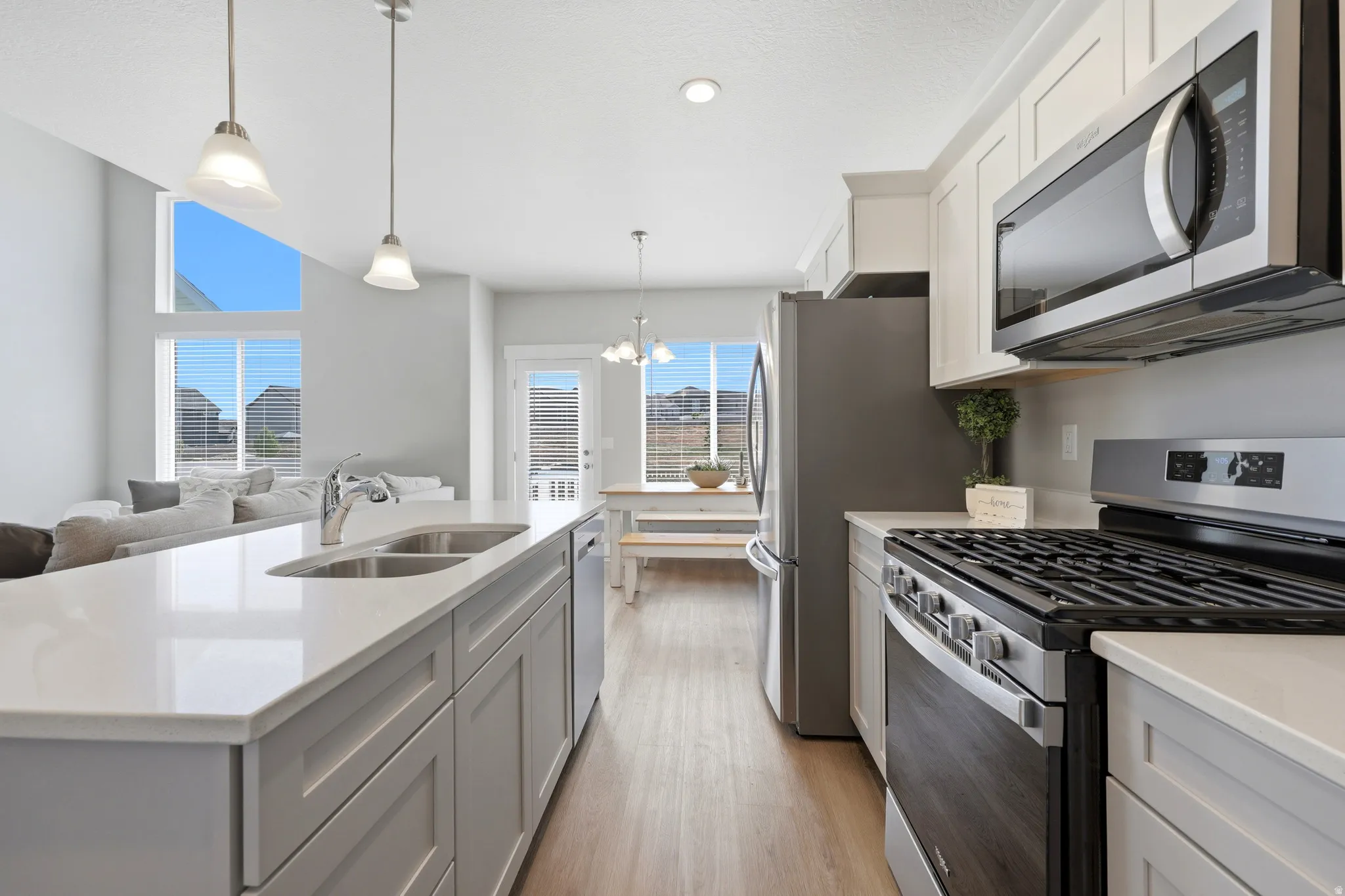 Kitchen featuring a double basin sink, stainless steel appliances, light-toned cabinetry, and light wood-finish flooring