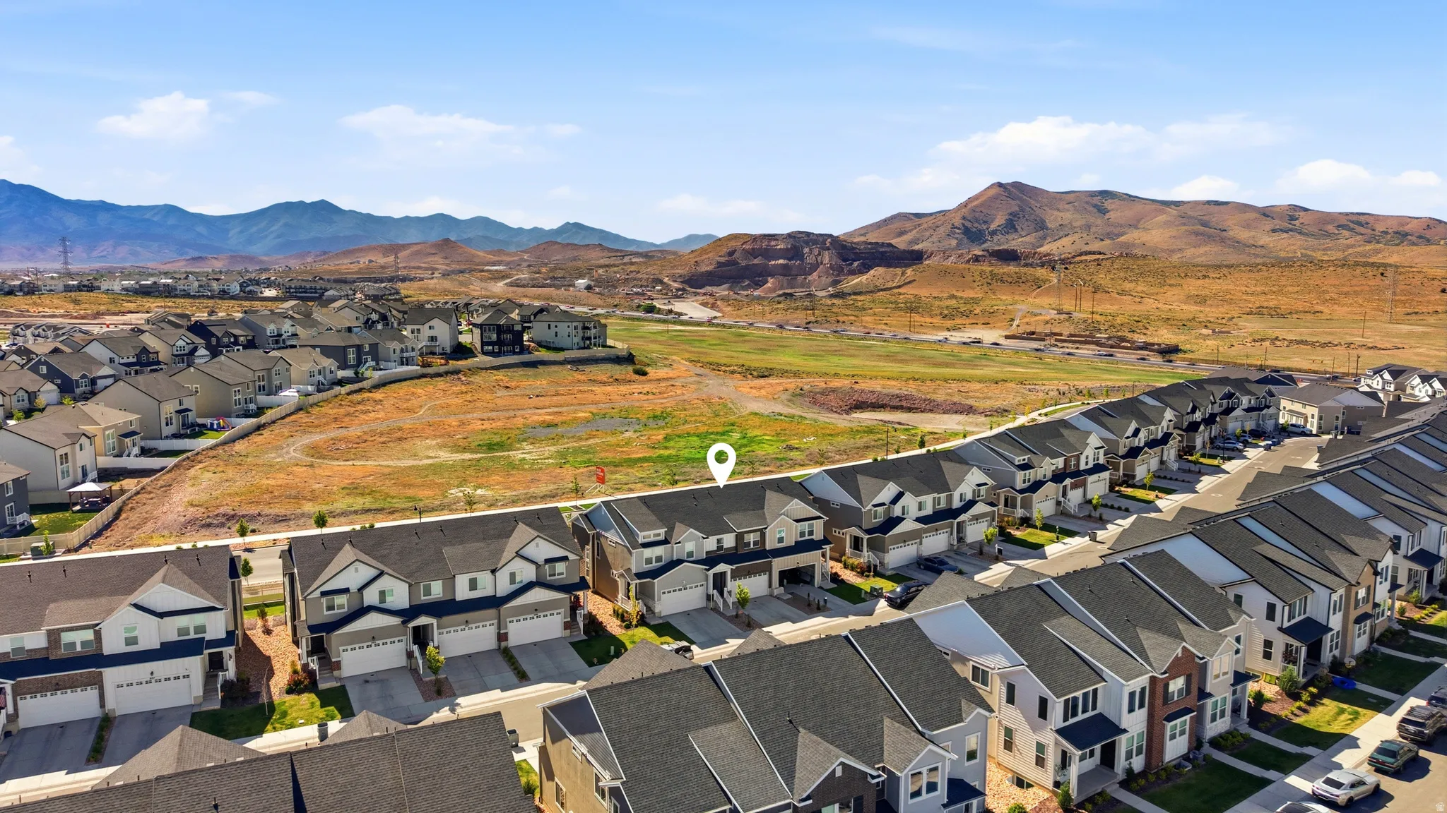 Aerial perspective showcasing a residential street with uniform two-story townhomes, each featuring a two-car garage