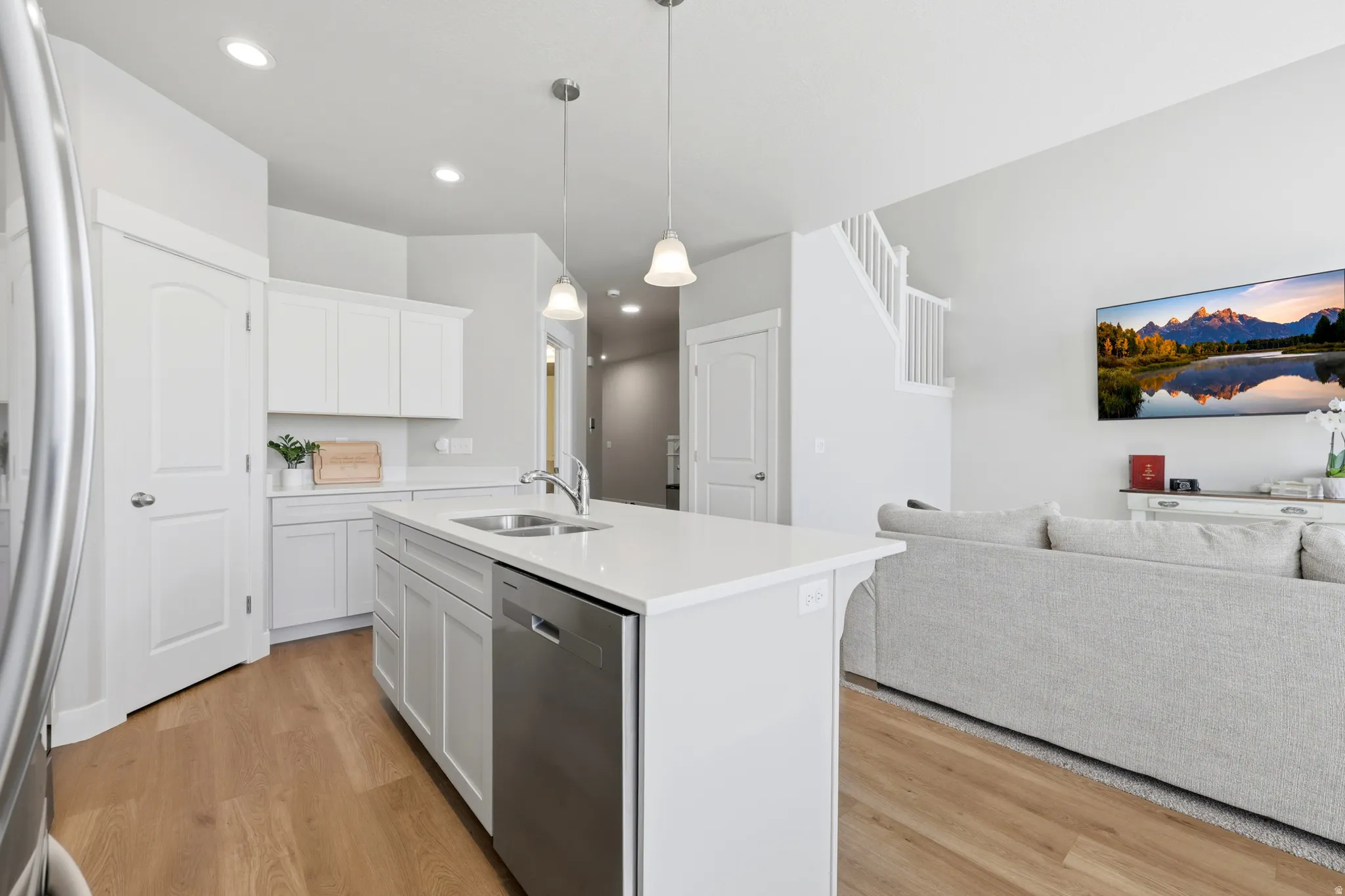 Kitchen island with integrated sink, stainless steel dishwasher, and pendant lighting