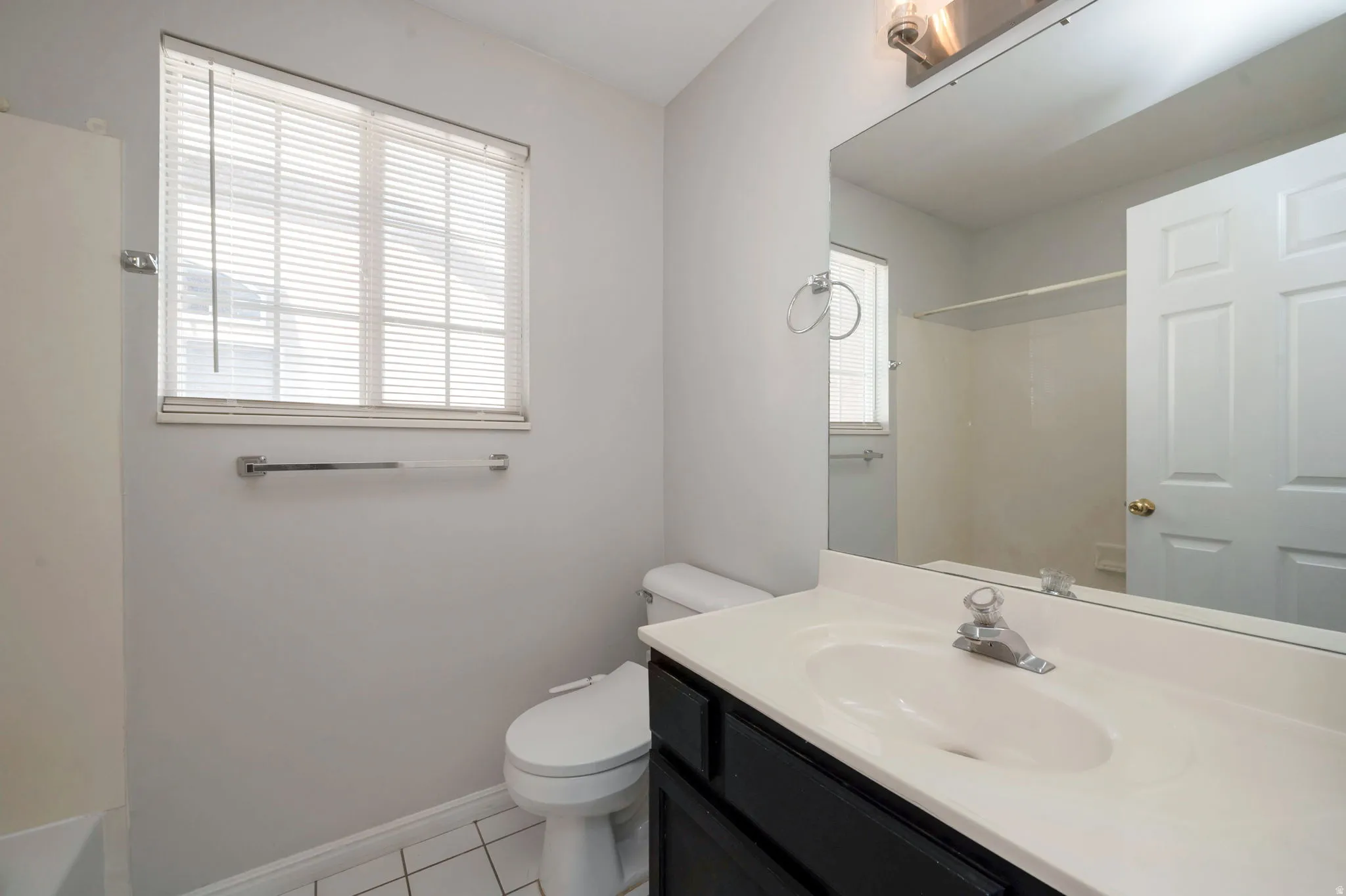 Bathroom featuring a white vanity with integrated sink, chrome faucet, and expansive wall mirror