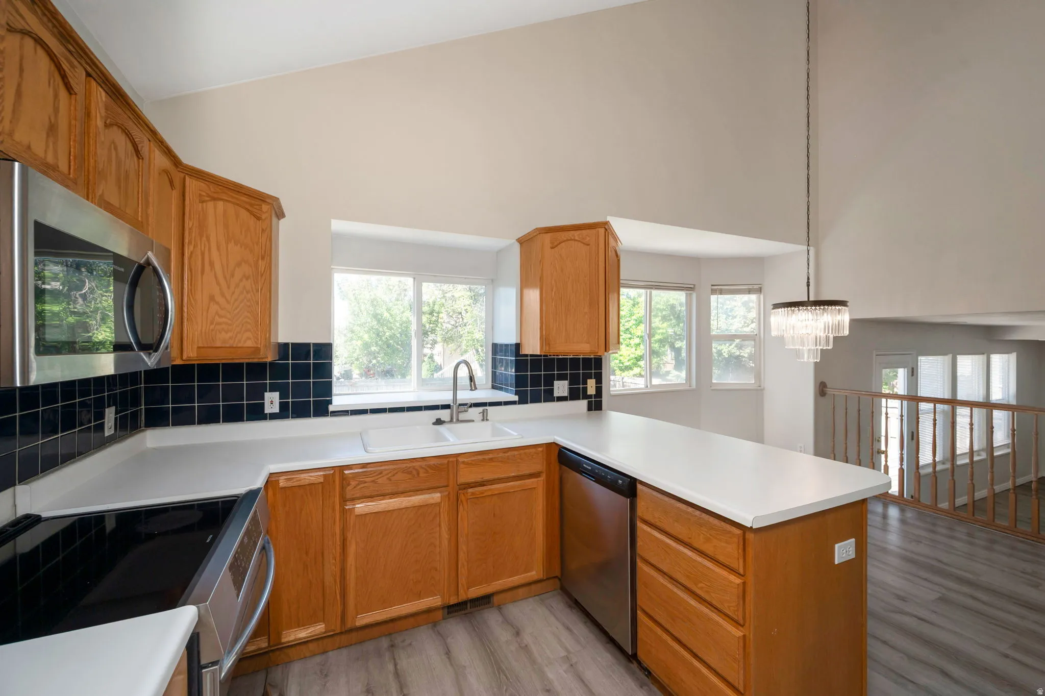 Kitchen featuring wood cabinetry, a double basin sink, stainless steel appliances, and wood-finish flooring