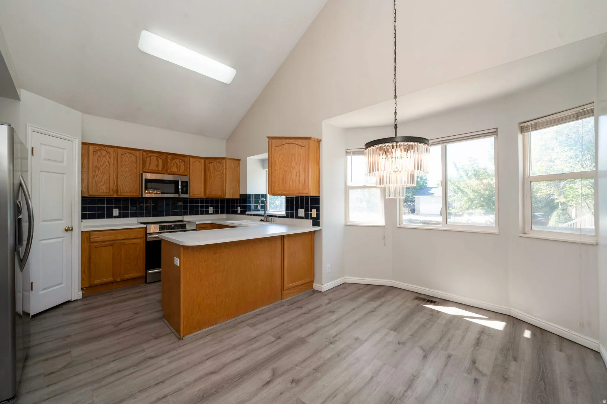 Kitchen and dining area featuring wood-finish flooring and vaulted ceilings