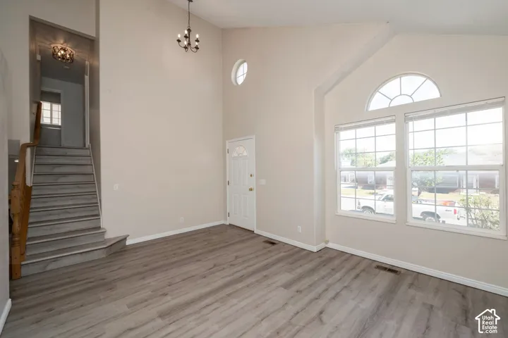 Vaulted living area featuring wood-finish flooring, a decorative chandelier, and an arched window with a transom