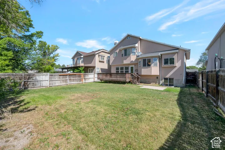 Expansive backyard featuring a wood deck, wood privacy fencing, and a stucco exterior