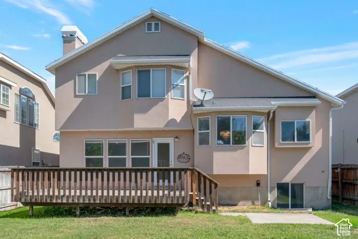 Rear exterior featuring a wooden deck, multiple windows, and a stucco finish