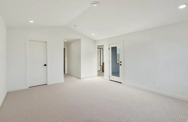 Spacious room with light-toned patterned carpeting, white walls, and recessed lighting