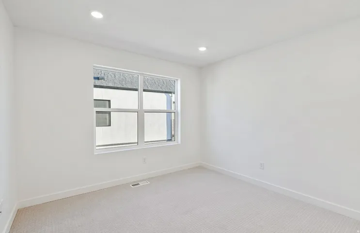 Bright room featuring a large multi-pane window, recessed lighting, white walls, white baseboards, and neutral-toned carpeting